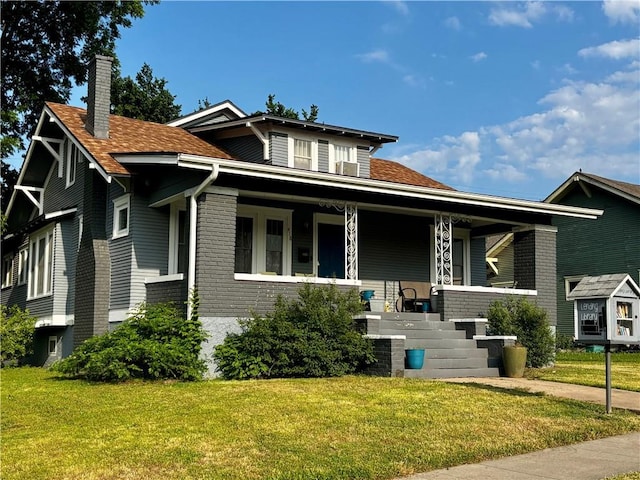 418 N 8th St, Independence, KS 67301 - view of front of property featuring a porch, a chimney, a front lawn, and brick siding