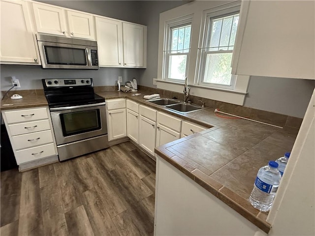 418 N 8th St, Independence, KS 67301 - kitchen with appliances with stainless steel finishes, a sink, white cabinetry, and dark wood-style flooring