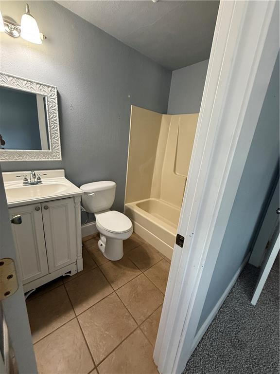 418 N 8th St, Independence, KS 67301 - bathroom with vanity, toilet, tile patterned flooring, and shower / washtub combination
