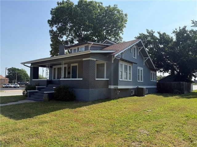 418 N 8th St, Independence, KS 67301 - view of property exterior featuring a lawn, central AC unit, covered porch, and brick siding