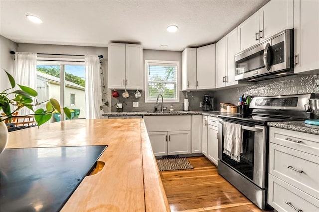 7041 Garnett St, Shawnee, KS 66203 - kitchen featuring appliances with stainless steel finishes, a sink, healthy amount of natural light, wood finished floors, and recessed lighting