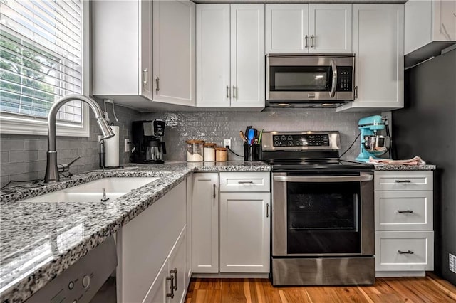 7041 Garnett St, Shawnee, KS 66203 - kitchen with stainless steel appliances, a sink, backsplash, and white cabinetry
