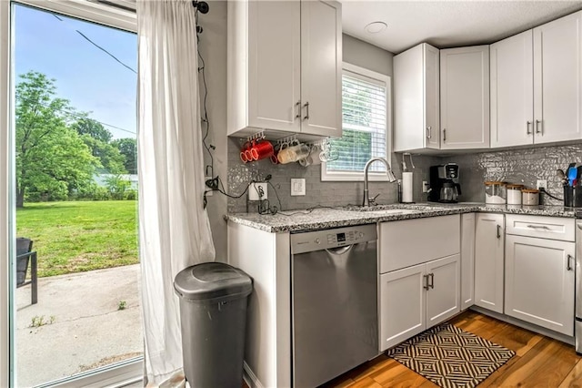 7041 Garnett St, Shawnee, KS 66203 - kitchen featuring stainless steel dishwasher, a sink, wood finished floors, and backsplash