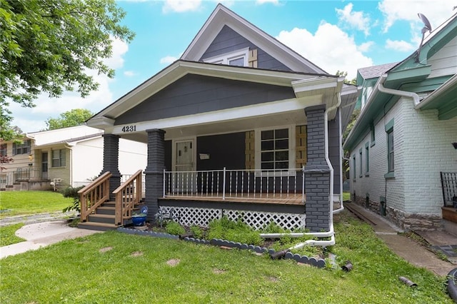 4231 Wyoming St, Kansas City, MO 64111 - shotgun-style home featuring covered porch, brick siding, and a front lawn