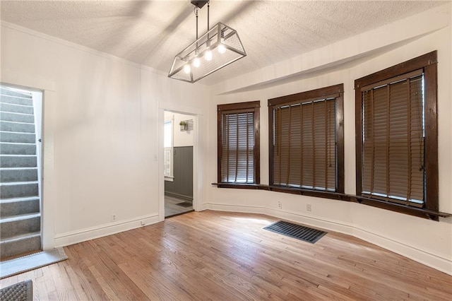 4231 Wyoming St, Kansas City, MO 64111 - unfurnished dining area featuring wood finished floors, a textured ceiling, baseboards, and stairway