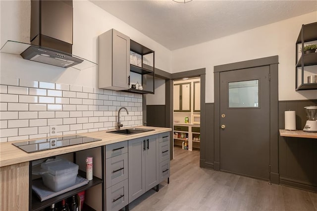 4231 Wyoming St, Kansas City, MO 64111 - kitchen featuring open shelves, black electric cooktop, a sink, custom range hood, and gray cabinets