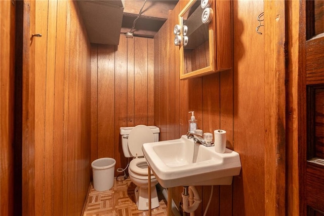 4231 Wyoming St, Kansas City, MO 64111 - half bathroom featuring toilet, wooden walls, and a sink