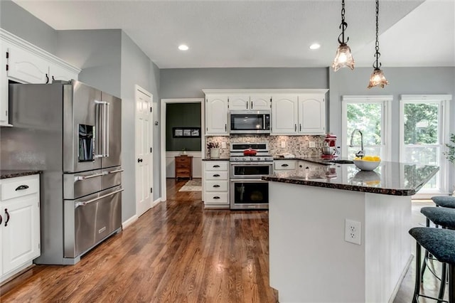 14169 W 115th Ter, Olathe, KS 66062 - kitchen with appliances with stainless steel finishes, white cabinetry, backsplash, dark wood-style flooring, and recessed lighting