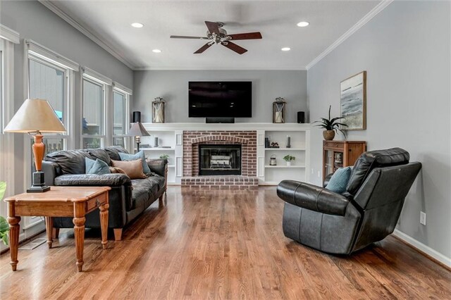 14169 W 115th Ter, Olathe, KS 66062 - living room featuring wood finished floors, a ceiling fan, ornamental molding, recessed lighting, and a brick fireplace
