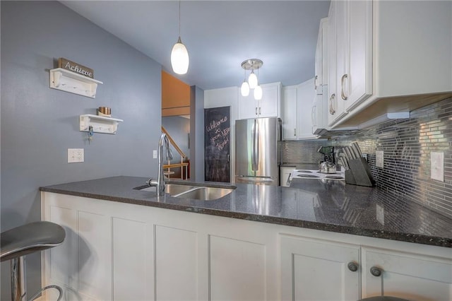 6520 W 51st St, Mission, KS 66202 - kitchen featuring freestanding refrigerator, a sink, decorative backsplash, dark stone counters, and a peninsula