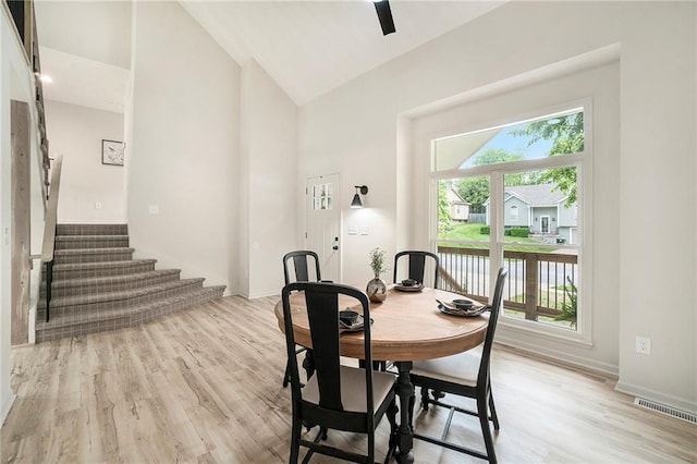 1345 NE Foxwood Dr, Lees Summit, MO 64086 - dining room featuring high vaulted ceiling, stairs, light wood finished floors, a water view, and baseboards