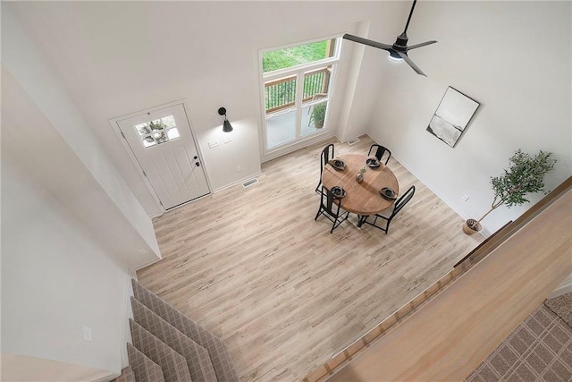 1345 NE Foxwood Dr, Lees Summit, MO 64086 - unfurnished living room featuring light wood-style floors, stairs, baseboards, a towering ceiling, and ceiling fan