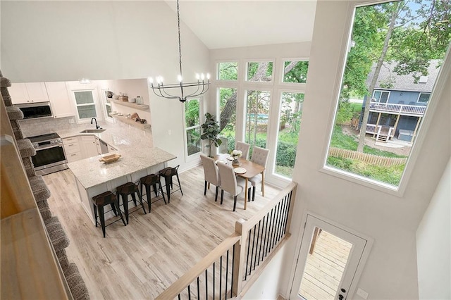 1345 NE Foxwood Dr, Lees Summit, MO 64086 - kitchen with a sink, electric range, high vaulted ceiling, a kitchen breakfast bar, and white cabinetry