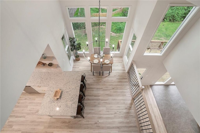 1345 NE Foxwood Dr, Lees Summit, MO 64086 - living room featuring a towering ceiling, a chandelier, plenty of natural light, and wood finished floors