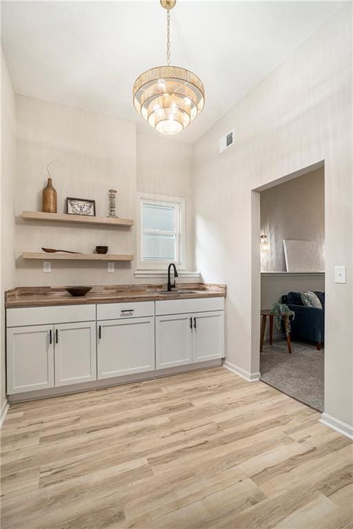 1345 NE Foxwood Dr, Lees Summit, MO 64086 - kitchen featuring light wood-style floors, butcher block counters, baseboards, a chandelier, and a sink