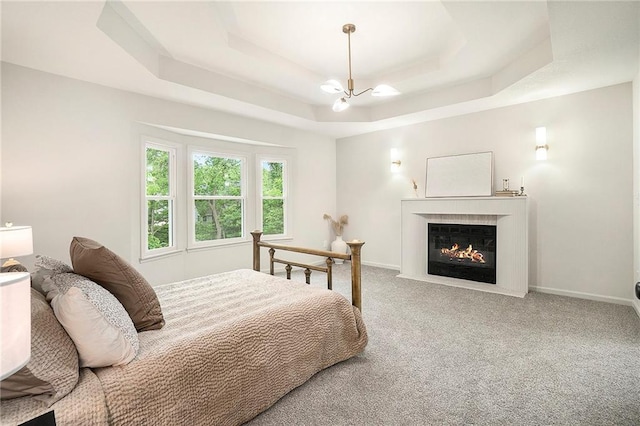 1345 NE Foxwood Dr, Lees Summit, MO 64086 - carpeted bedroom featuring a raised ceiling, a chandelier, a fireplace with flush hearth, and baseboards