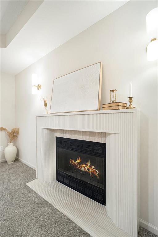 1345 NE Foxwood Dr, Lees Summit, MO 64086 - detailed view of a lit fireplace, baseboards, and carpet
