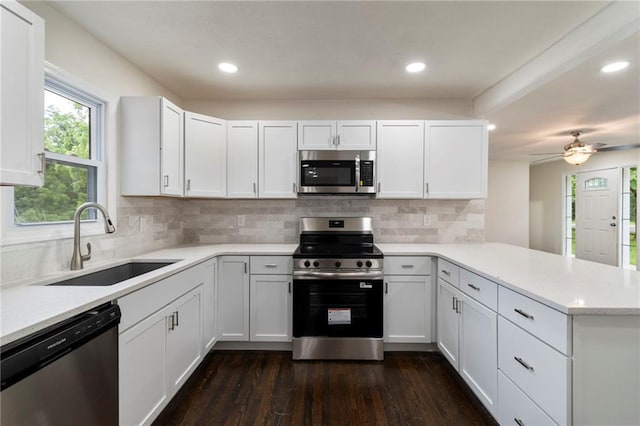6201 N Topping Ave, Kansas City, MO 64119 - kitchen with appliances with stainless steel finishes, a sink, a peninsula, dark wood-style floors, and white cabinets