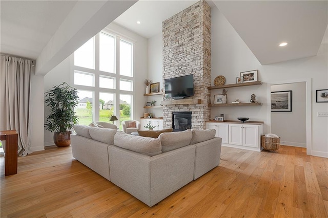1120 Hillswick Ln, Raymore, MO 64083 - living area with high vaulted ceiling, baseboards, a stone fireplace, and light wood finished floors
