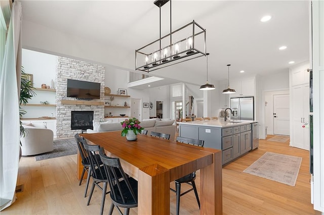 1120 Hillswick Ln, Raymore, MO 64083 - dining space with light wood-style floors, a stone fireplace, and recessed lighting