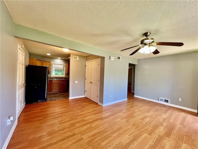 1208 E 80th St, Kansas City, MO 64131 - empty room featuring light wood finished floors, a textured ceiling, a sink, ceiling fan, and baseboards
