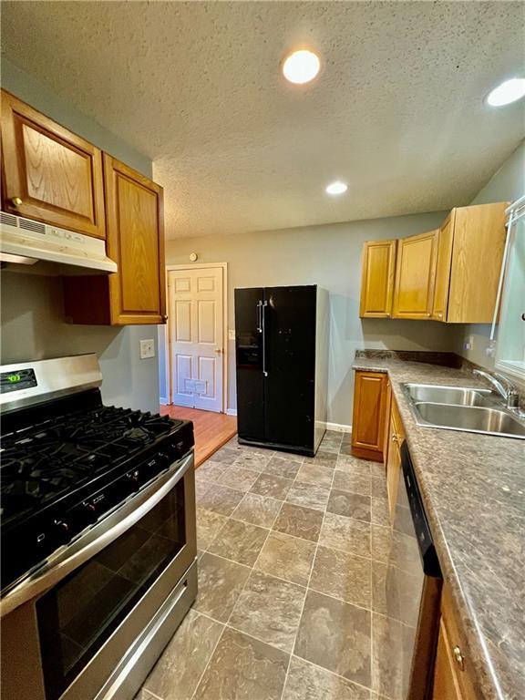 1208 E 80th St, Kansas City, MO 64131 - kitchen featuring stainless steel appliances, under cabinet range hood, a sink, a textured ceiling, and recessed lighting