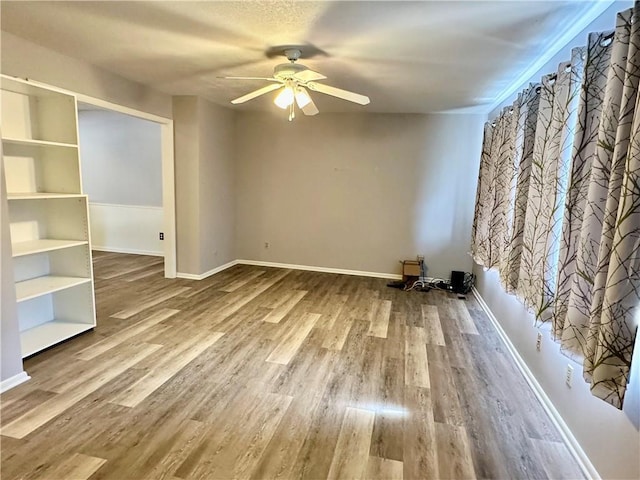 1220 N 76th Ter, Kansas City, KS 66112 - unfurnished living room featuring ceiling fan, wood finished floors, and baseboards