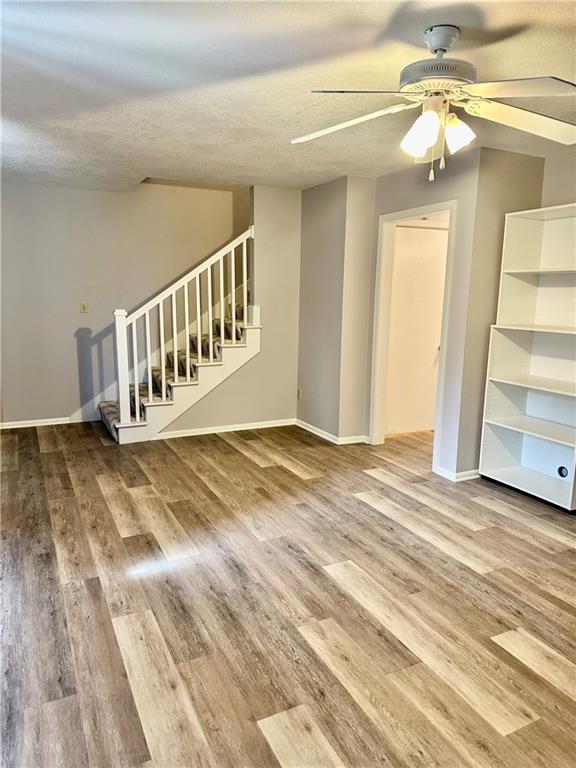 1220 N 76th Ter, Kansas City, KS 66112 - unfurnished living room with ceiling fan, stairway, wood finished floors, baseboards, and a textured ceiling