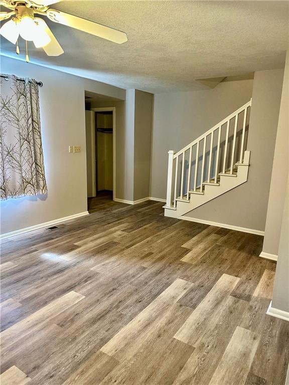 1220 N 76th Ter, Kansas City, KS 66112 - unfurnished room with wood finished floors, stairway, baseboards, a ceiling fan, and a textured ceiling