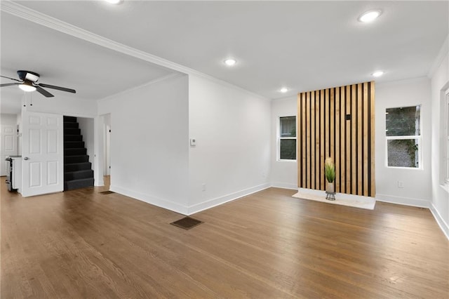 5227 Highland Ave, Kansas City, MO 64110 - unfurnished living room with stairway, dark wood-type flooring, a ceiling fan, baseboards, and ornamental molding
