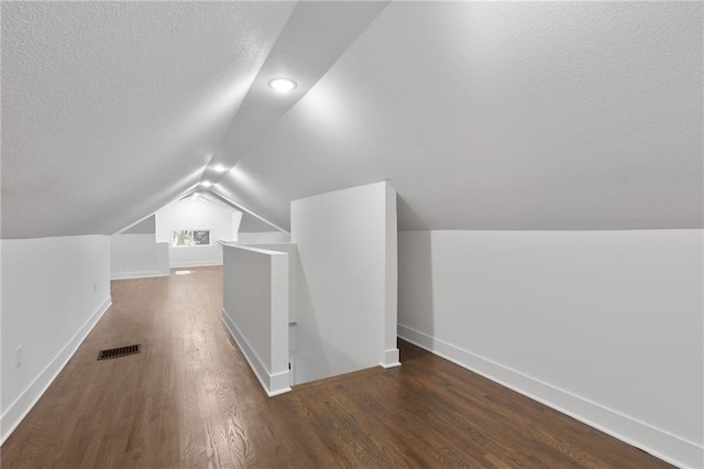 5227 Highland Ave, Kansas City, MO 64110 - bonus room featuring a textured ceiling, wood finished floors, baseboards, and lofted ceiling
