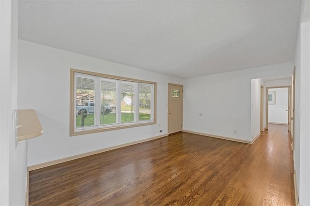 10720 Sycamore Ter, Kansas City, MO 64134 - unfurnished living room with wood finished floors, a textured ceiling, and baseboards