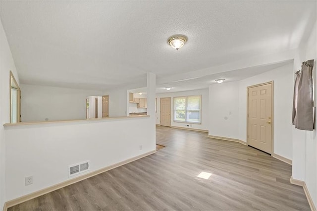10720 Sycamore Ter, Kansas City, MO 64134 - unfurnished living room featuring a textured ceiling, wood finished floors, and baseboards