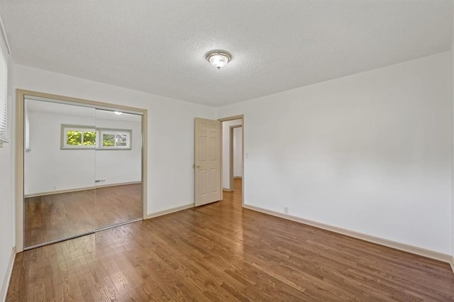 10720 Sycamore Ter, Kansas City, MO 64134 - unfurnished bedroom featuring wood finished floors, baseboards, a textured ceiling, and a closet