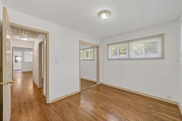 10720 Sycamore Ter, Kansas City, MO 64134 - unfurnished bedroom with wood finished floors, a closet, a textured ceiling, and baseboards