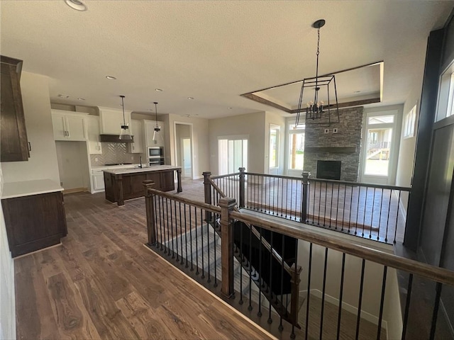 1516 SW Arborpark Ter, Lees Summit, MO 64082 - hallway featuring dark wood-style flooring, a raised ceiling, a textured ceiling, recessed lighting, and an upstairs landing
