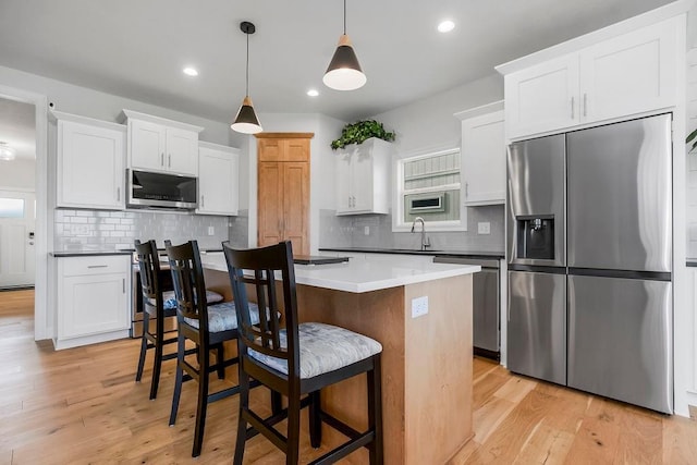 17756 Shady Bend Rd, Gardner, KS 66030 - kitchen with stainless steel appliances, a kitchen island, a breakfast bar area, light wood finished floors, and recessed lighting