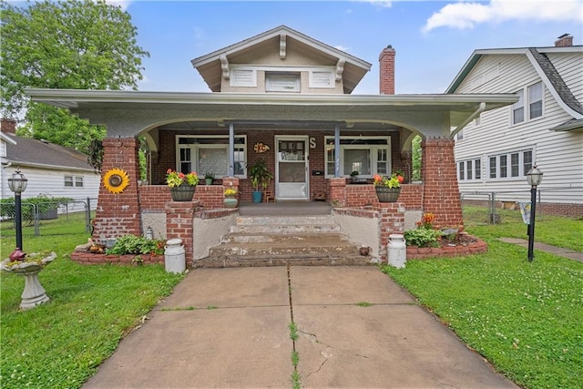 313 N 11th St, Independence, KS 67301 - bungalow-style home with brick siding, a porch, and a chimney