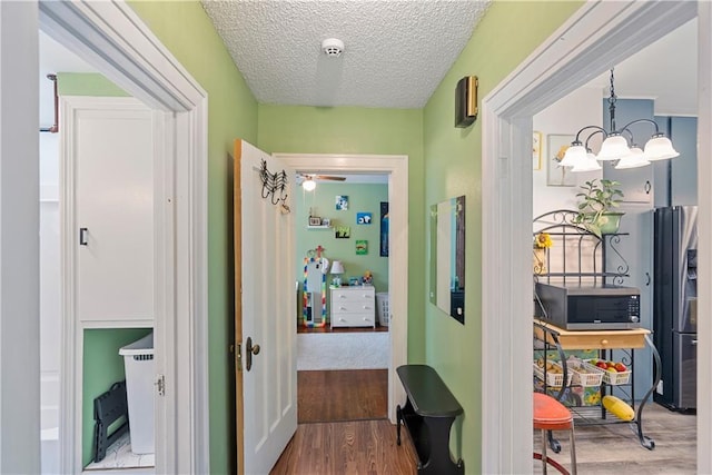 313 N 11th St, Independence, KS 67301 - corridor featuring wood finished floors, a textured ceiling, and a chandelier