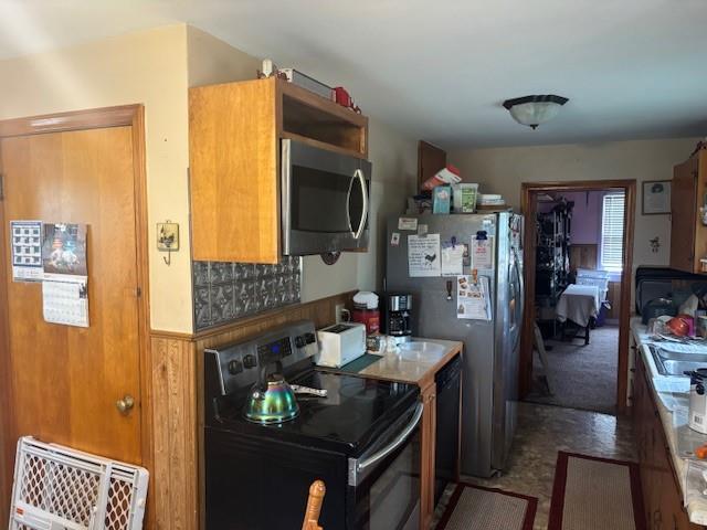 1119 Mound St, Atchison, KS 66002 - kitchen with stainless steel appliances, brown cabinetry, and a wainscoted wall