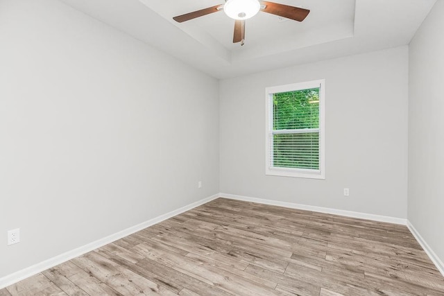 7515 Locust Dr, Kansas City, MO 64152 - unfurnished room with a tray ceiling, light wood-style flooring, and ceiling fan