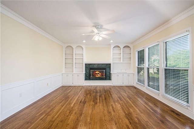 8901 W 128th St, Overland Park, KS 66213 - unfurnished living room featuring a tiled fireplace, built in features, dark wood-style flooring, ceiling fan, and ornamental molding