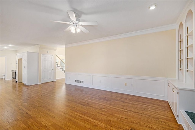 8901 W 128th St, Overland Park, KS 66213 - unfurnished living room featuring ceiling fan, wood finished floors, stairs, built in shelves, and crown molding