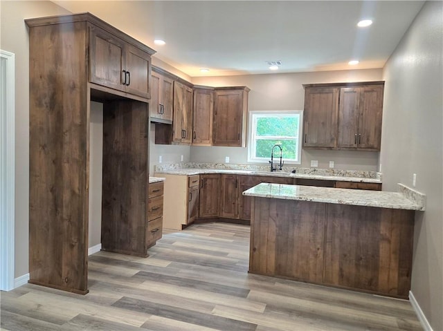 1101 Lakewood Dr, Pittsburg, KS 66762 - kitchen featuring a sink, light wood-type flooring, a peninsula, light stone counters, and baseboards