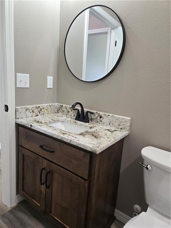 1101 Lakewood Dr, Pittsburg, KS 66762 - bathroom with vanity, toilet, wood finished floors, and baseboards