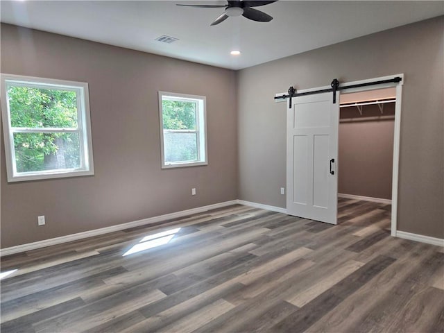 1101 Lakewood Dr, Pittsburg, KS 66762 - unfurnished bedroom with a barn door, baseboards, wood finished floors, a walk in closet, and recessed lighting