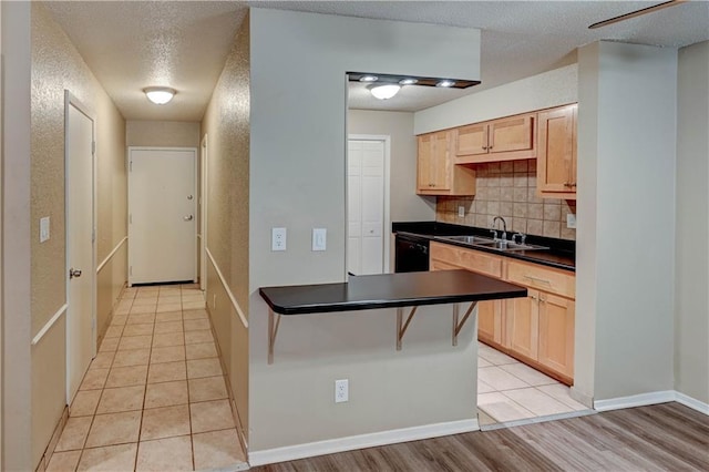4157 Roanoke Rd Unit 2, Kansas City, MO 64111 - kitchen with a sink, dark countertops, tasteful backsplash, black dishwasher, and light brown cabinets