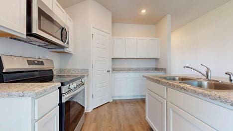 567 W Fountain St, Gardner, KS 66030 - kitchen featuring appliances with stainless steel finishes, white cabinetry, light wood-type flooring, a sink, and recessed lighting
