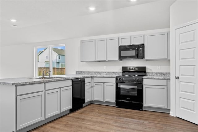 597 W Fountain St, Gardner, KS 66030 - kitchen with black appliances, a sink, a peninsula, light wood-style flooring, and recessed lighting