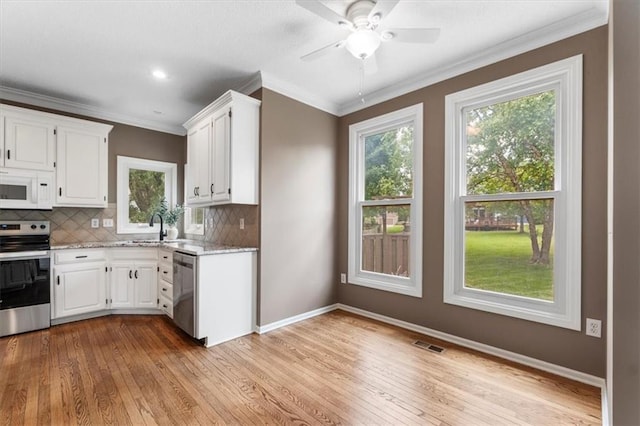 14155 W 147th Ter, Olathe, KS 66062 - kitchen featuring appliances with stainless steel finishes, light wood finished floors, healthy amount of natural light, white cabinetry, and crown molding